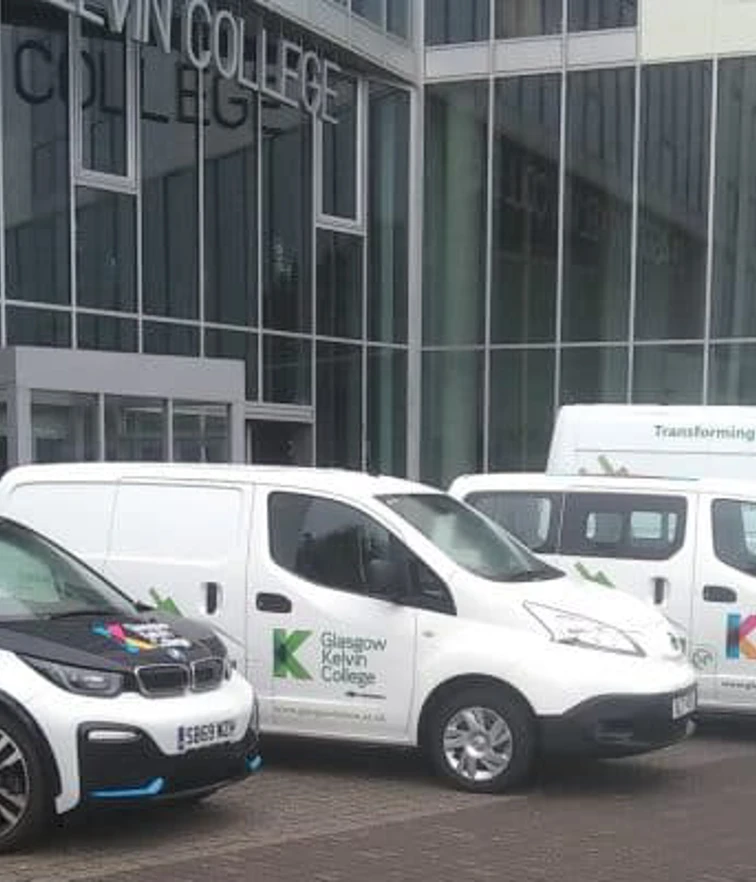 Fleet of electric vehicles branded with Glasgow Kelvin College logos parked outside the college's modern glass-fronted building. Fleet of electric vehicles branded with Glasgow Kelvin College logos parked outside the college's modern glass-fronted building.